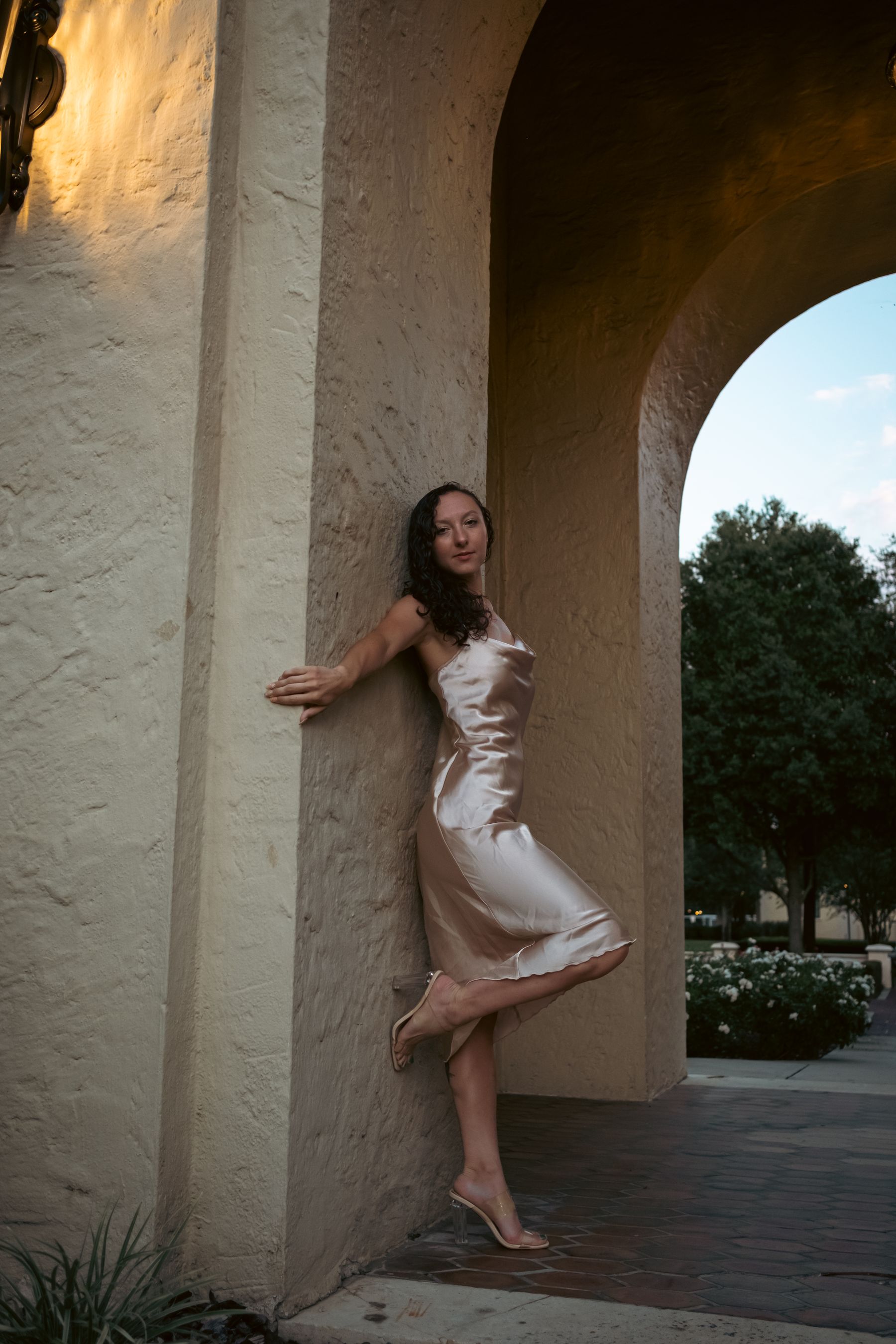 Woman in a silk dress beneath an arched colonnade